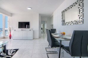 Een moderne eetruimte met een glazen tafel, zwarte stoelen en een wit kastje.