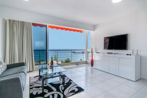 A modern living room with a glass table, a sofa, a flat-screen TV, and a view of the sea. - La Estrella 1A020 con vistas panorámicas al mar (Los Cristianos)