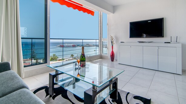 A modern living room with a glass coffee table, a flat-screen TV, and a view of the sea. - La Estrella 1A020 con vistas panorámicas al mar (Los Cristianos)