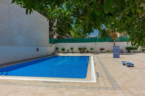 A swimming pool with a clear blue water, surrounded by a tiled deck and a low wall. - La Estrella 1A020 con vistas panorámicas al mar (Los Cristianos)
