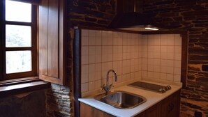 A kitchen with a stone wall, a wooden cabinet, a sink, and a window.