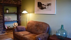 A cozy living room with a leather sofa, a framed artwork, a lamp, and a decorative vase.