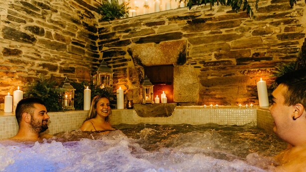A stone-walled hot tub area with candles and a tiled floor.