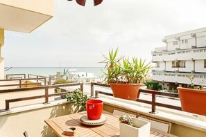 Un balcon avec une table en bois, des plantes en pot et une tasse rouge.