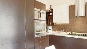 Una cocina moderna con electrodomésticos integrados, armarios de madera y encimera blanca.