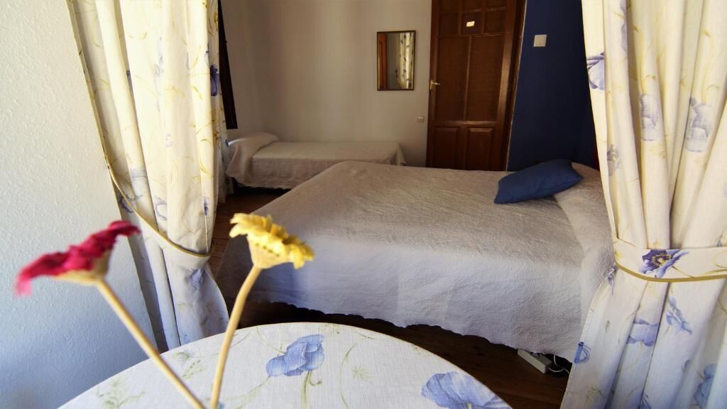 Een slaapkamer met twee bedden, een houten garderobe en een spiegel aan de muur.