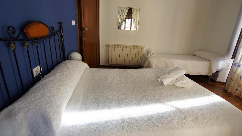 Un dormitorio con dos camas, un radiador, una ventana con cortinas y una puerta.