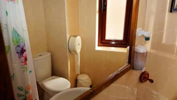 Un baño pequeño con inodoro, bidé y ventana.