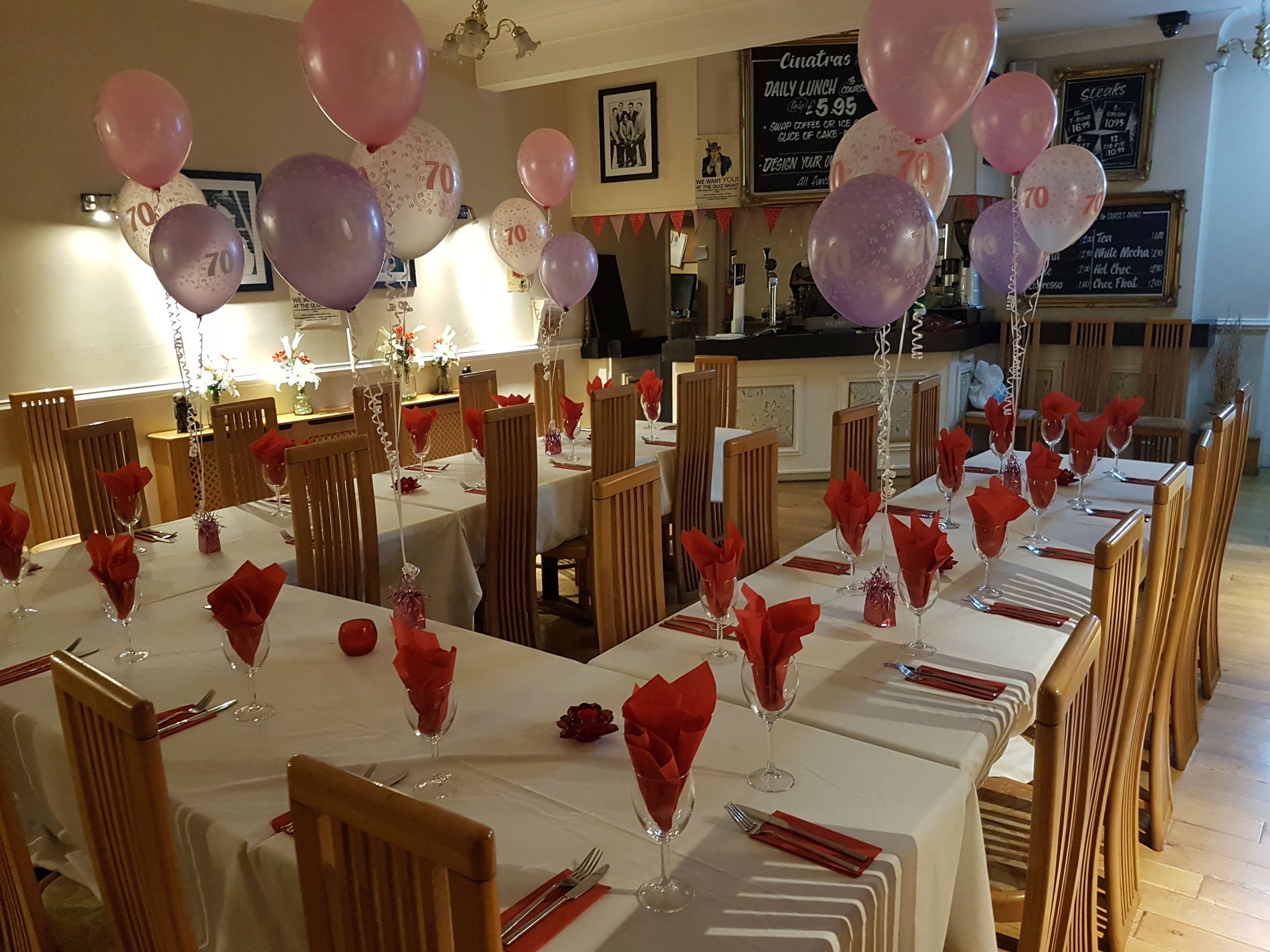 A restaurant with tables set for dining, balloons, and a menu board in the background.