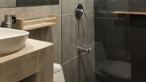 A modern bathroom with a glass shower enclosure, a beige sink, and a large mirror. - Condominios Las Navieras (Tamarindo)