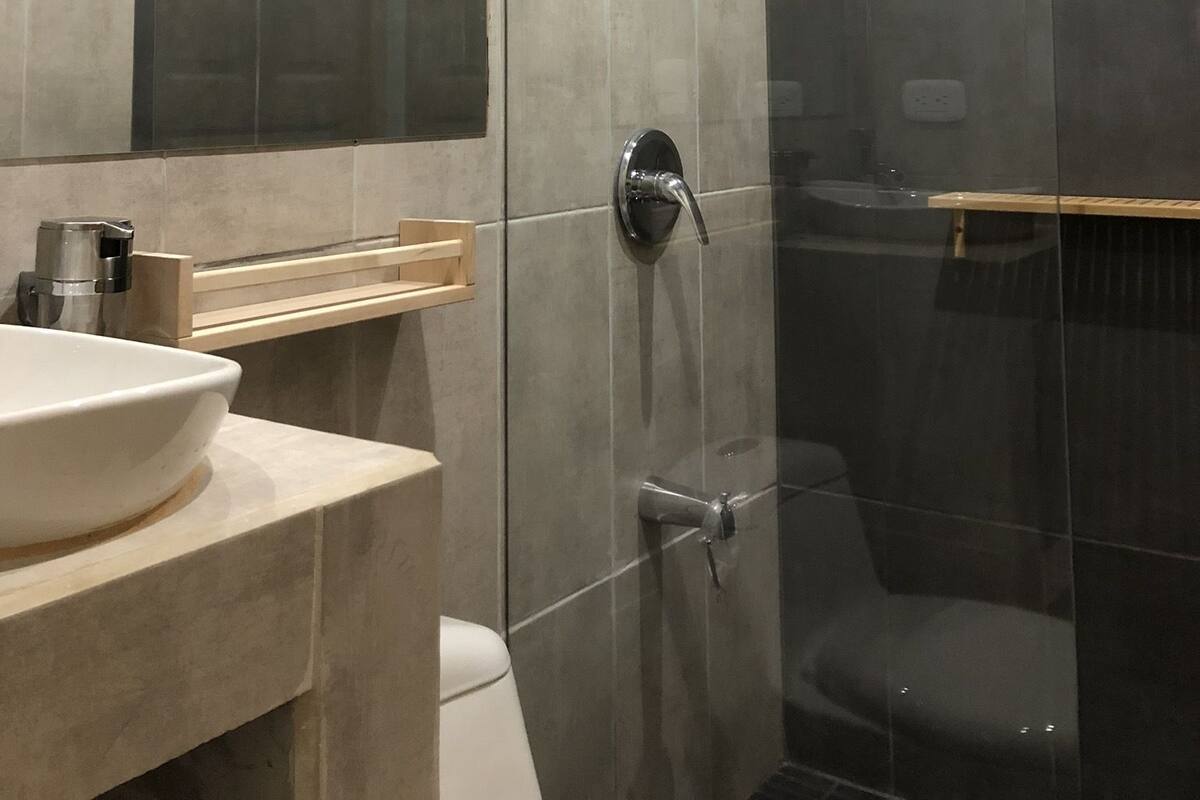 A modern bathroom with a glass shower enclosure, a beige sink, and a large mirror.