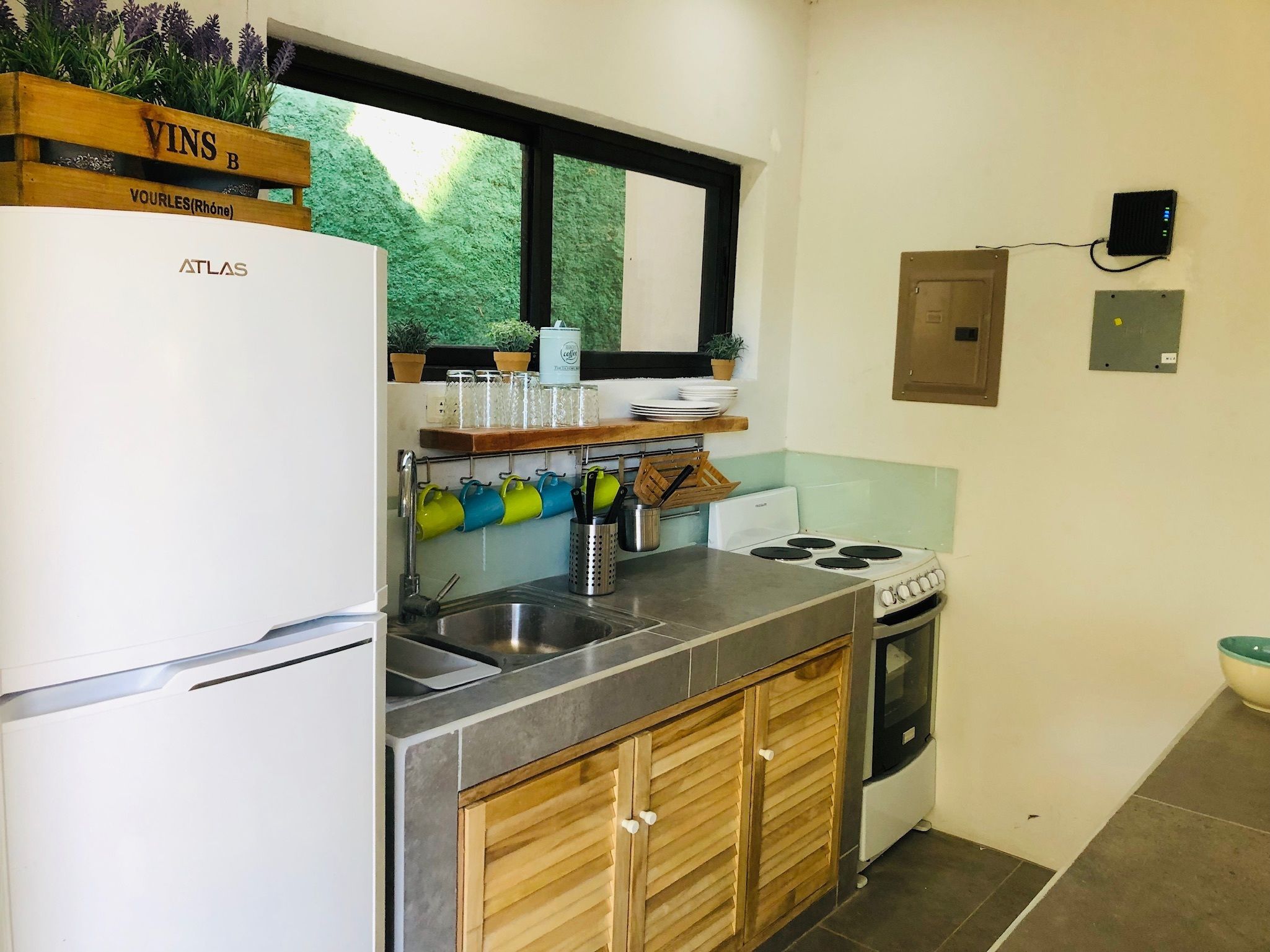 A compact kitchen with a refrigerator, stove, sink, and wooden cabinets.