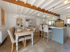 A dining area with a wooden table set for six, a kitchen with a central island, and a ceiling with exposed beams. - 7 bedroom accommodation in Bradbourne, near Ashbourne (Bradbourne, near Ashbourne)