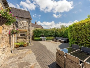 Un bâtiment en pierre doté d’un patio pavé, d’un espace extérieur aménagé pour s’asseoir et d’un barbecue.
