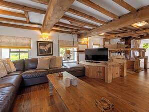 A cozy living room with a leather sofa, wooden coffee table, and a TV on a wooden stand. - 7 bedroom accommodation in Bradbourne, near Ashbourne (Bradbourne, near Ashbourne)