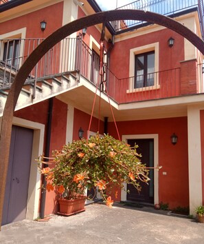 Un bâtiment à la façade rouge et blanche, doté d’un balcon et d’une plante suspendue.