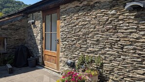 A stone building with a wooden door, outdoor seating, and potted plants. - Spacious, luxury,  romantic Barn for couples near Exmoor & Coast  (Bratton Fleming, Barnstaple)