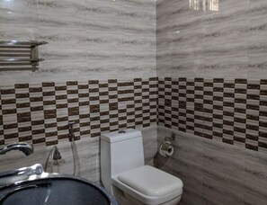 Bathroom features a modern design with a checkered tile border, white toilet, sink, and shower area with glass enclosure.