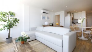 A modern living room with a white sofa, a wooden coffee table, and a potted plant. - Picasso Boutique (Torremolinos)