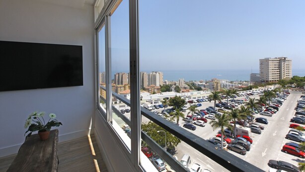 A balcony with a view of a parking lot, buildings, and the sea. - Picasso Boutique (Torremolinos)