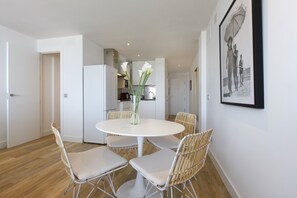 A dining area with a round table, white chairs, and a vase with flowers. - Picasso Boutique (Torremolinos)