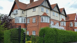A multi-story residential building with a brick facade, multiple windows, and a gated entrance. - 3 bedroom accommodation in Scarborough (Scarborough)
