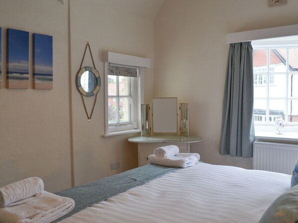 Un dormitorio con cama, ventana con cortinas, espejo y decoración en la pared.