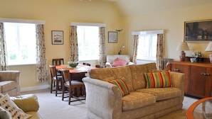 A living room with a sofa, armchairs, a dining table, and a glass coffee table. - 3 bedroom accommodation in Scarborough (Scarborough)