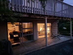 A modern house with a wooden deck, large windows, and a swing chair. - Raglan Harbour View Hotel (Raglan)