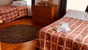 Habitación de hotel con dos camas, un aparador de madera, un espejo y un ventanal con cortinas.