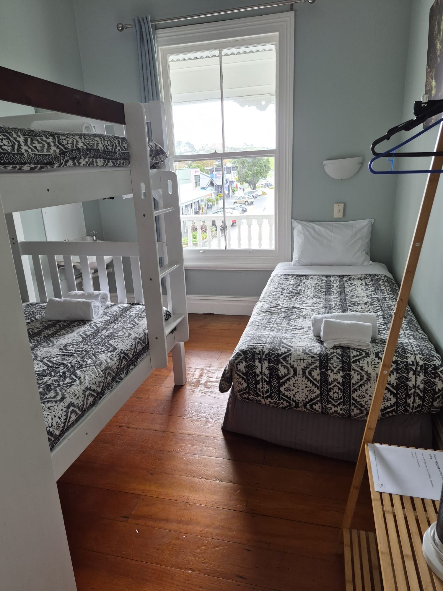 A room with bunk beds, a window with a view, and a wooden floor.