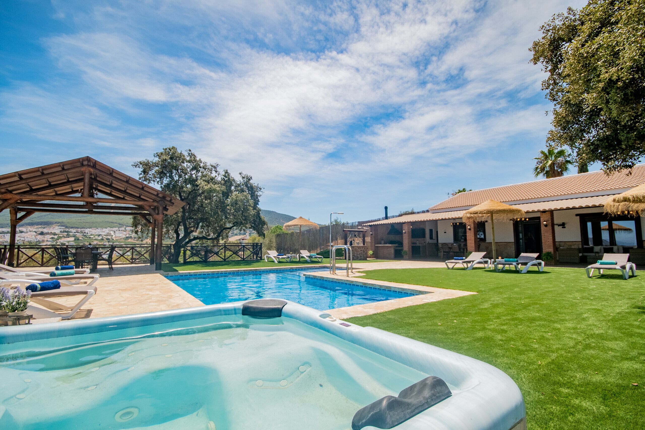 A swimming pool with lounge chairs, a pergola, and a view of the landscape.