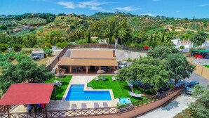 Una villa con piscina, mobiliario de exterior y vistas a las colinas circundantes.