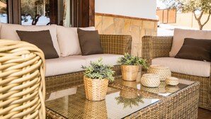 Un conjunto de sofá de mimbre con cojines, una mesa de centro de vidrio y cestas tejidas con plantas.
