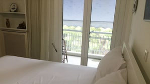 A bedroom with a bed, a window with a view of a balcony, and a shelf with decorative items. - APARTMENT IN THE CENTER (Athens)