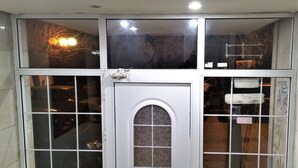 A white double door with a small arched window, flanked by two large windows with grid panes. - APARTMENT IN THE CENTER (Athens)