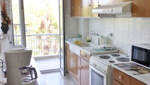 A kitchen with wooden cabinets, a stove, a microwave, and a coffee maker. - APARTMENT IN THE CENTER (Athens)