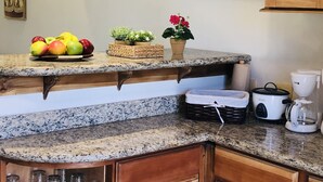 Uma bancada de cozinha com uma fruteira, plantas em vasos e uma cafeteira.