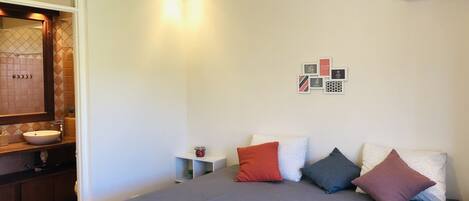 A hotel room with a bed, a bathroom with a sink, and a wall-mounted air conditioner.