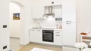 Cozinha moderna com armários brancos, coifa de aço inoxidável, forno embutido e pia.