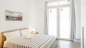 Quarto de hotel com uma cama, mesa de cabeceira, um quadro e porta de vidro deslizante.