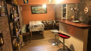 Un coin bar accueillant, avec un plancher en bois, un comptoir, des tabourets et une table recouverte d’une nappe matelassée.