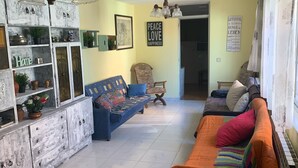 Un salon comprenant un canapé, un fauteuil et un meuble agrémenté d’objets décoratifs.