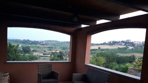 A balcony with wicker furniture and a view of a rural landscape. - LITTLE FROG on UNESCO Piedmont Langhe Monferrato WINE HILLS. Garden BBQ pingpong (agliano terme)