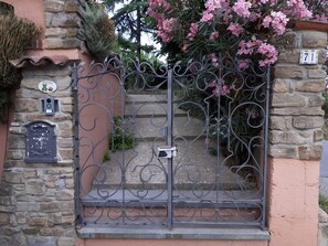 Une porte en fer forgé, un mur en pierre et une boîte aux lettres.