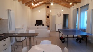 A modern living room with a ping pong table, white furniture, a brick wall, and a large window. - LITTLE FROG on UNESCO Piedmont Langhe Monferrato WINE HILLS. Garden BBQ pingpong (agliano terme)