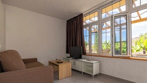 A living room with a sofa, TV, and a small table. - GC0282 Holiday house with shared pool in Mogán (Mogán)