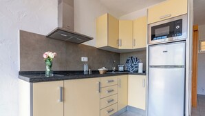 A modern kitchen with a built-in microwave, a stainless steel refrigerator, and a vase with flowers on the countertop. - GC0282 Holiday house with shared pool in Mogán (Mogán)