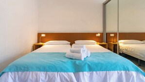A hotel room with a bed, two bedside tables with lamps, a mirror, and a stack of folded towels. - GC0282 Holiday house with shared pool in Mogán (Mogán)