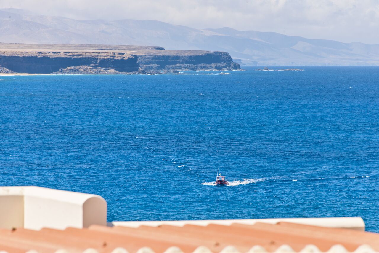 Une vue sur la côte, avec un bateau sur l’eau et des falaises en arrière-plan.